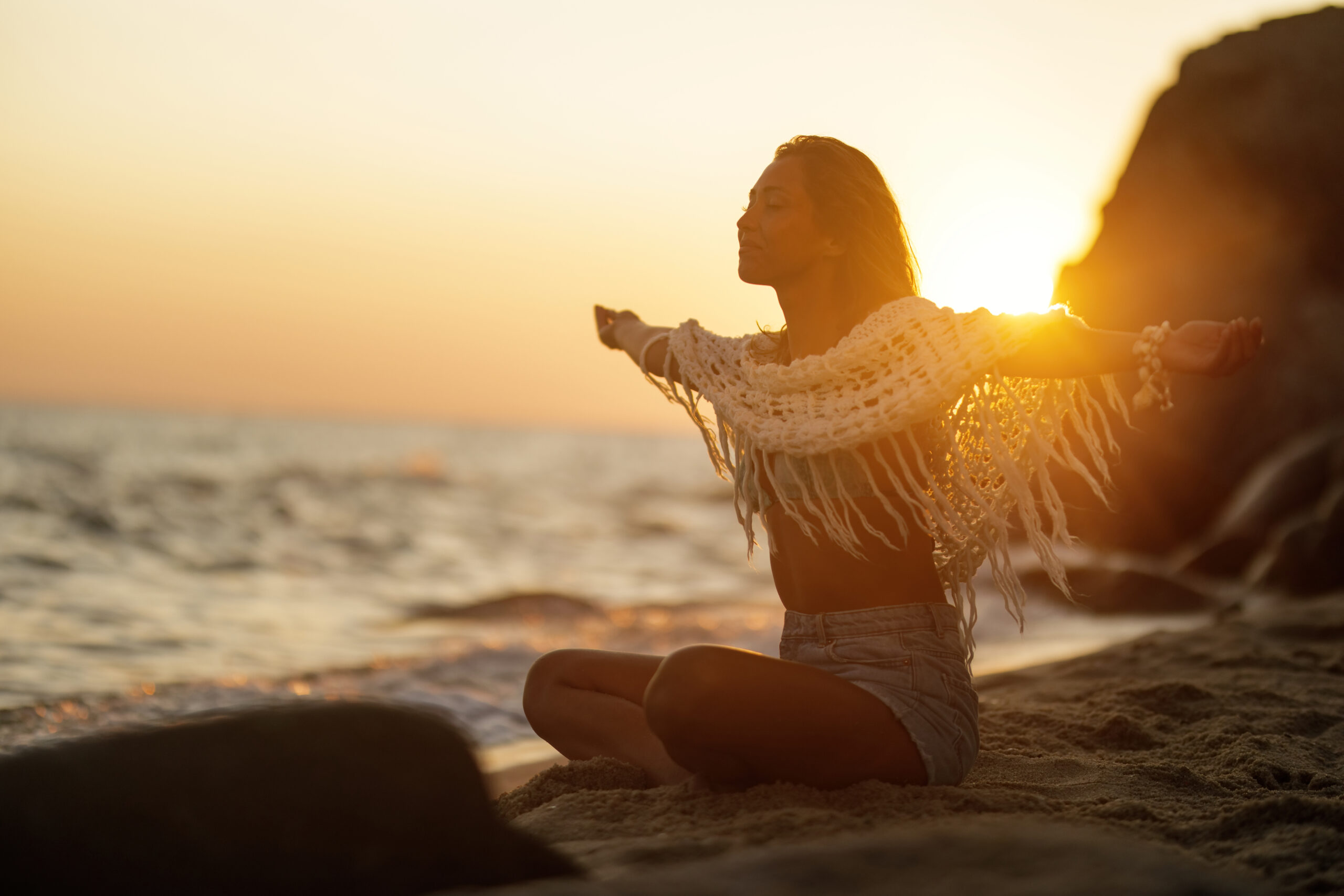 Smiling woman with arms outstretched feeling free at summer sunset.